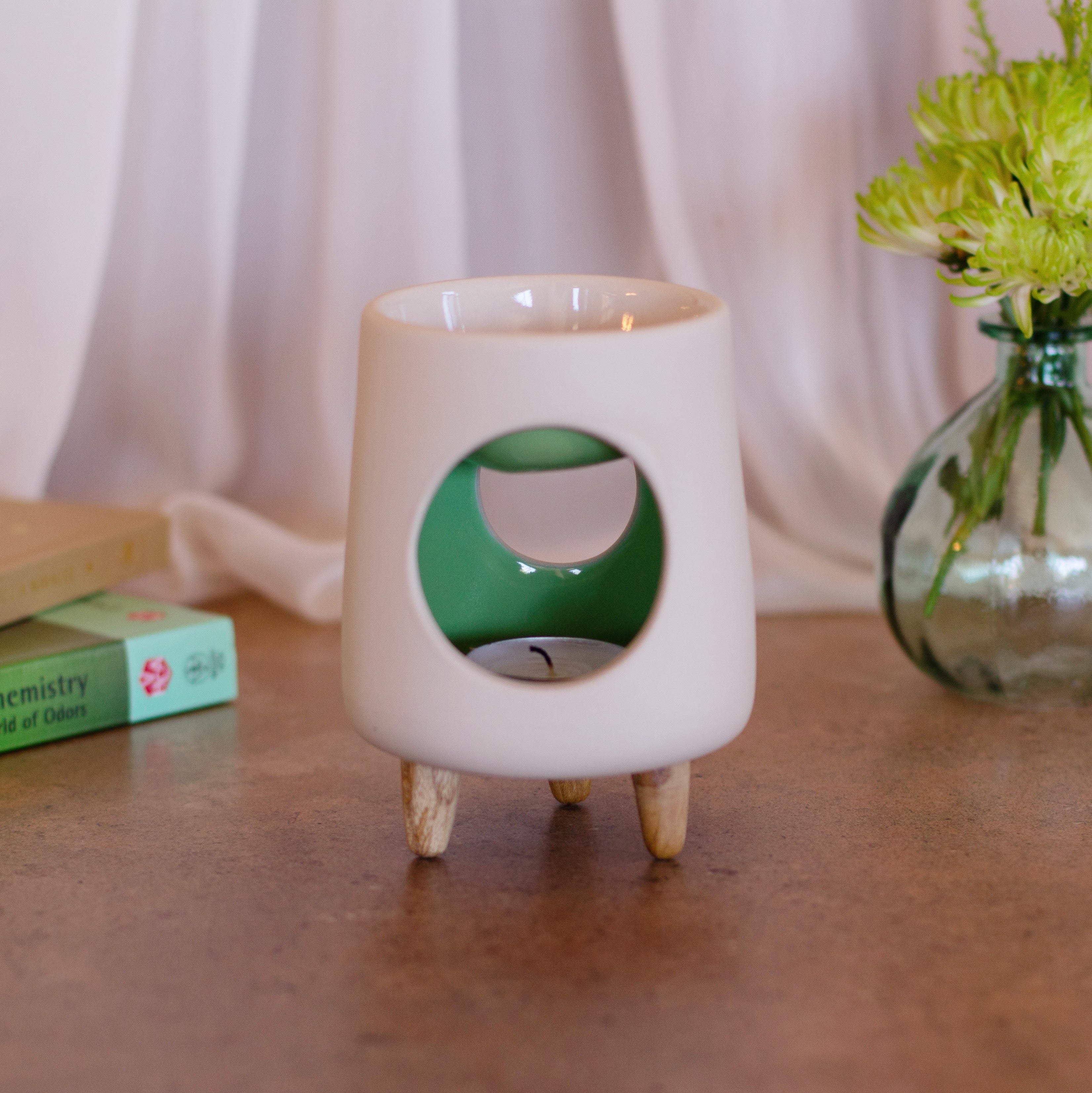 Ceramic wax warmer essential oil warmer by Arya Tara Candles. White outside green inside colored. Ceramic handmade tealight wax warmer with wooden legs.