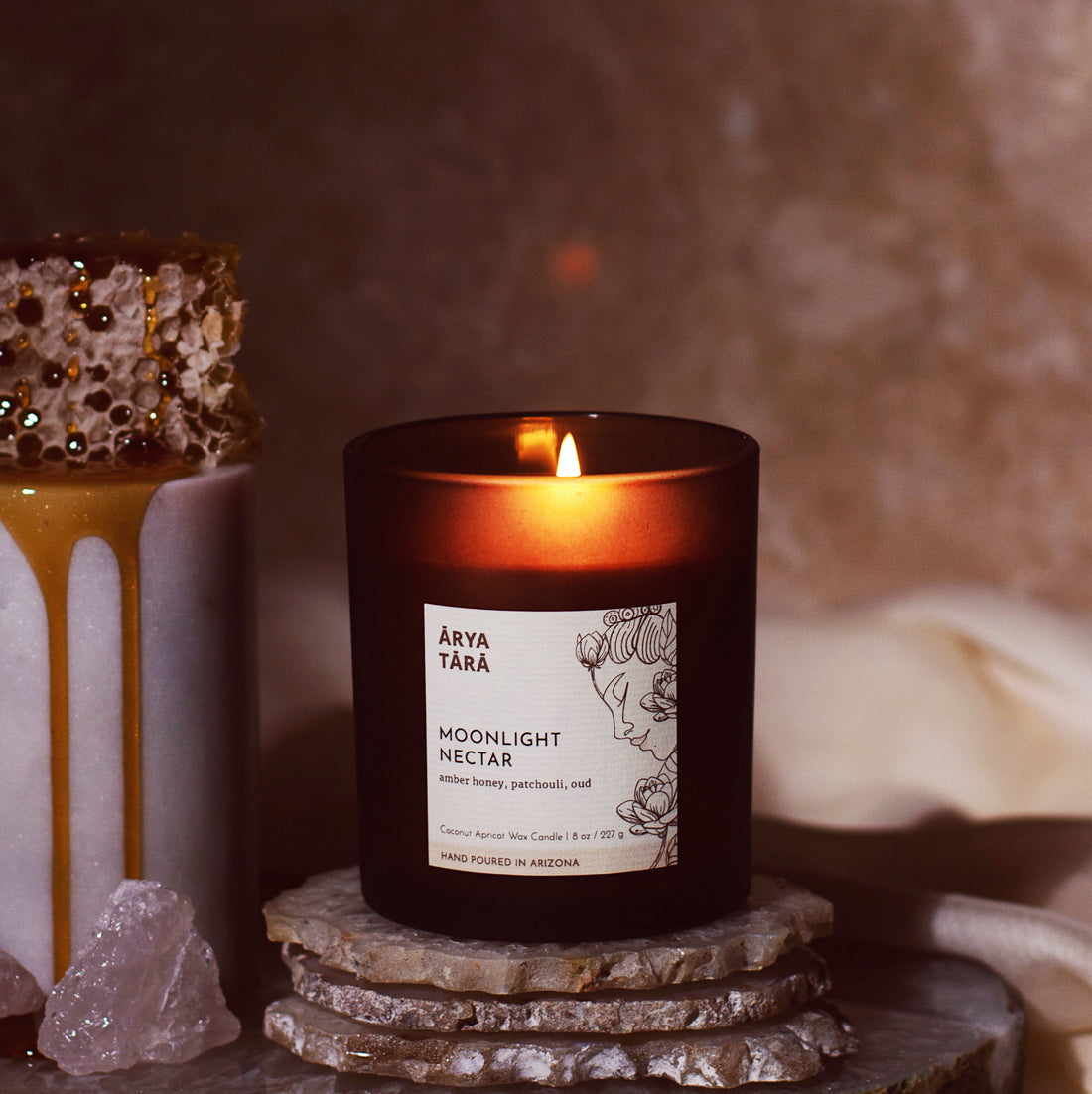 Moonlight Nectar Candle Fall Collection by Arya Tara Candles. Amber honey, beeswax, elemi, clove leaf, patchouli, oud, vanilla, dark chocolate. Non-toxic natural candle made with coconut apricot wax, lead-free zinc-free wicks, premium fragrances. Perfect autumn scented candle for fall decor home design home fragrances. Luxury candle, natural candle. Made in Tucson Arizona, hand poured candle in small batch. Dark brown glass jar candle with bamboo wooden lid.
