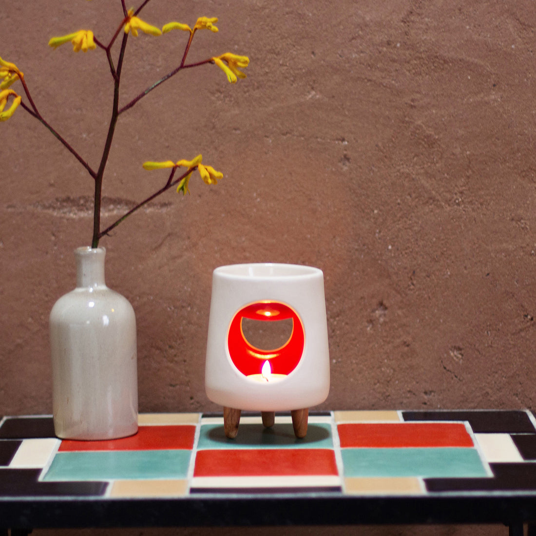 Ceramic wax warmer essential oil warmer by Arya Tara Candles. White outside red inside colored. Ceramic handmade tealight wax warmer with wooden legs.