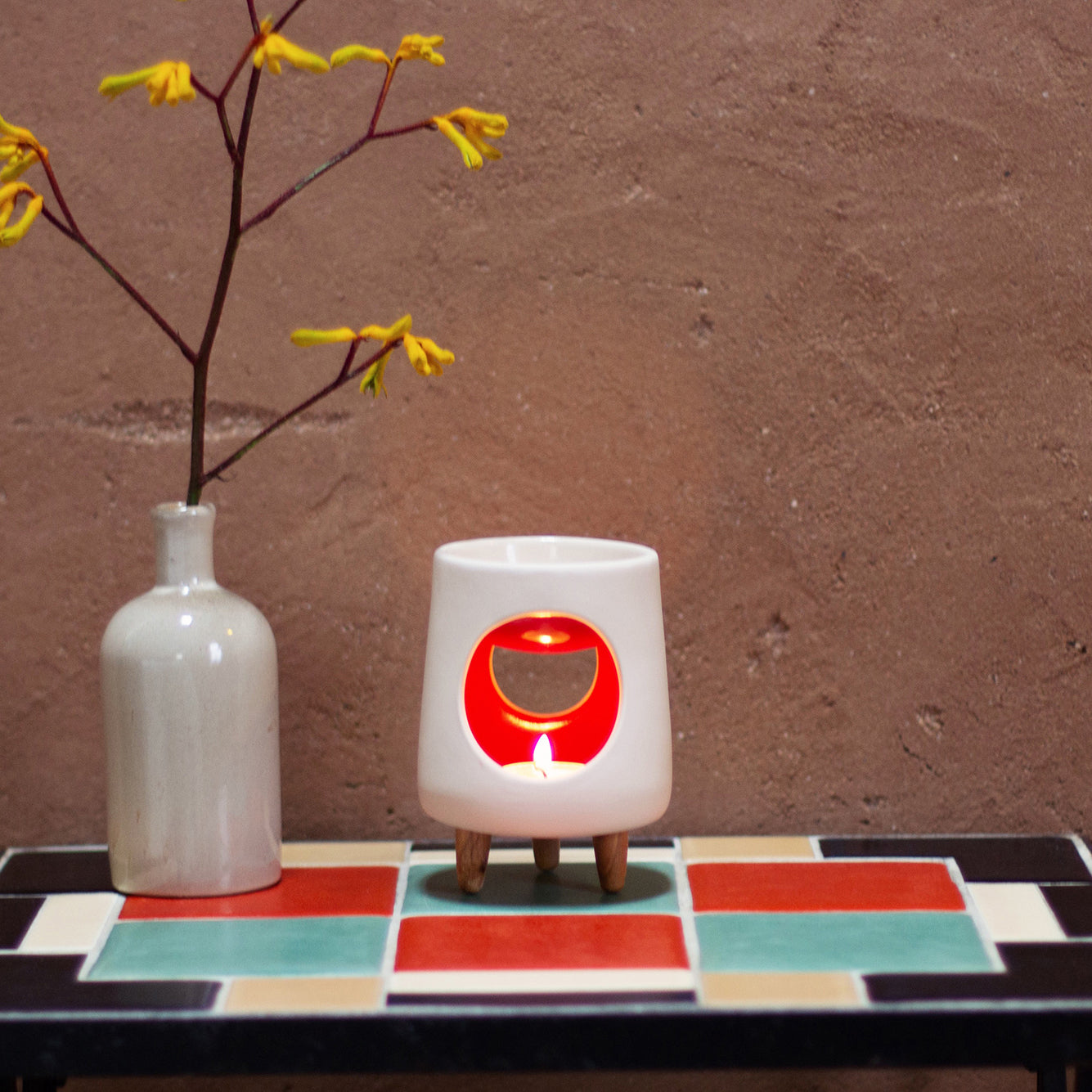 Ceramic wax warmer essential oil warmer by Arya Tara Candles. White outside red inside colored. Ceramic handmade tealight wax warmer with wooden legs.