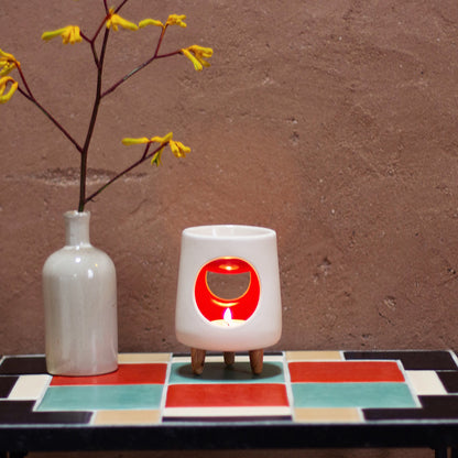 Ceramic wax warmer essential oil warmer by Arya Tara Candles. White outside red inside colored. Ceramic handmade tealight wax warmer with wooden legs.